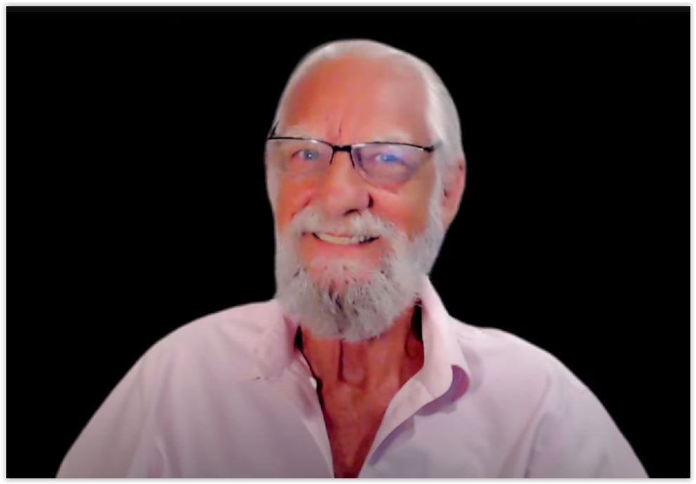 Rich West smiling, wearing glasses and a pink shirt